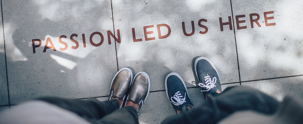 two pairs of feet stand close to a statement etched into the sidewalk that says "passion led us here'